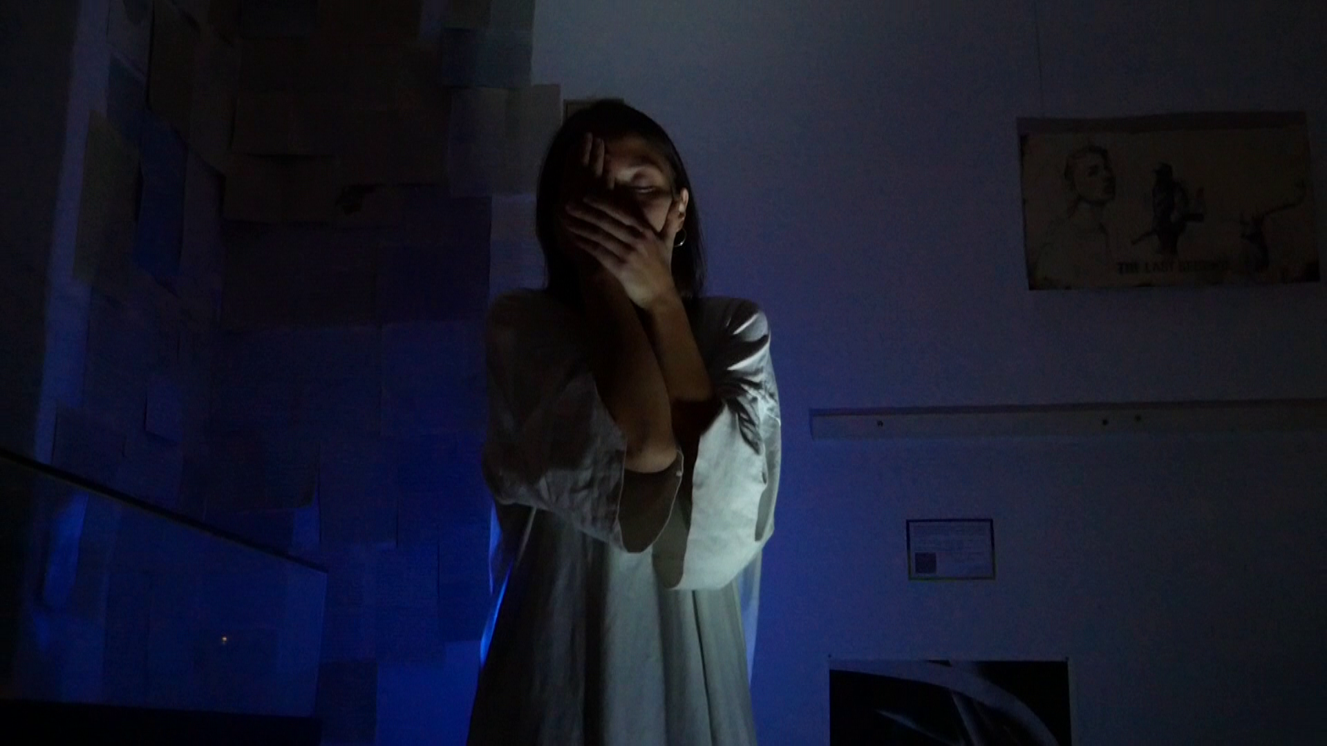 A woman is standing in pose, resembling the sculpture of Käthe Kolwitz 'Die Klage'.